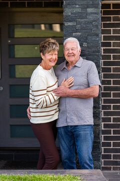 happy smiling senior Australian couple together outside front door of home