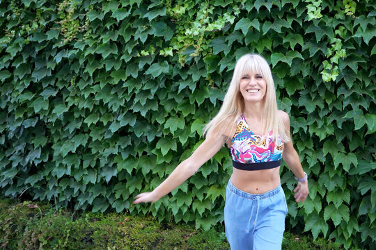 Woman dancing outdoors in front of ivy wall