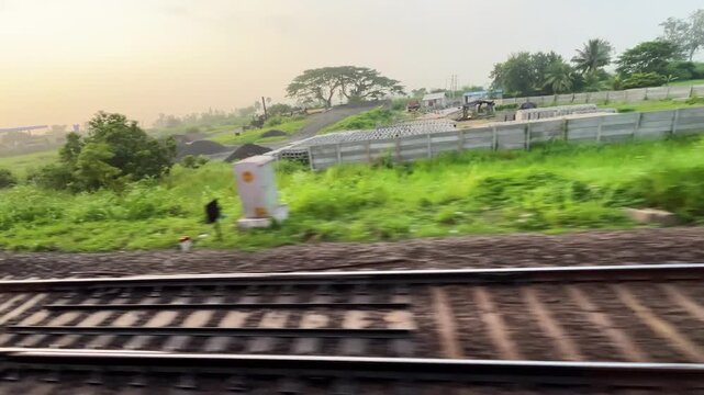 Window View of Fast Moving Indian Train Passing Parallel Tracks and Green Countryside. Close Up View of Parallel Railway Tracks and Concrete Sleepers from Moving Passenger Train.