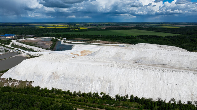Huge white industrial hills under dramatic summer clouds in Lithuania