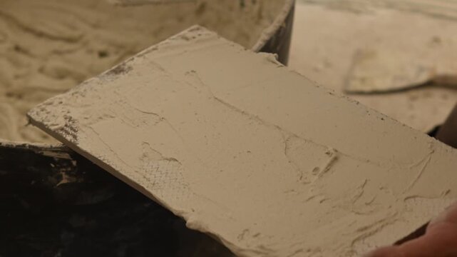 Construction worker applying adhesive to a tile