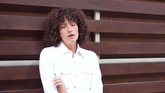 A Stylish Woman with Beautiful Curly Hair Posing Against a Modern and Trendy Background