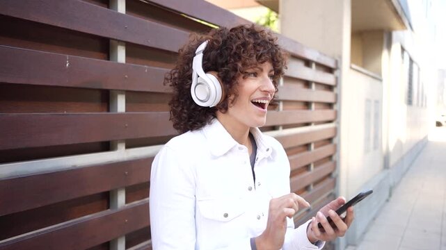 A Woman Happily Enjoying Music While Using Her Smartphone in a Vibrant Urban Environment