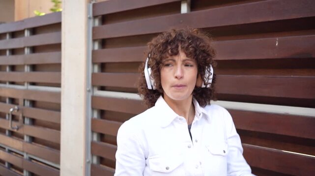 A Joyful Woman Who Is Happily Enjoying Music Outdoors While Wearing Comfortable Headphones