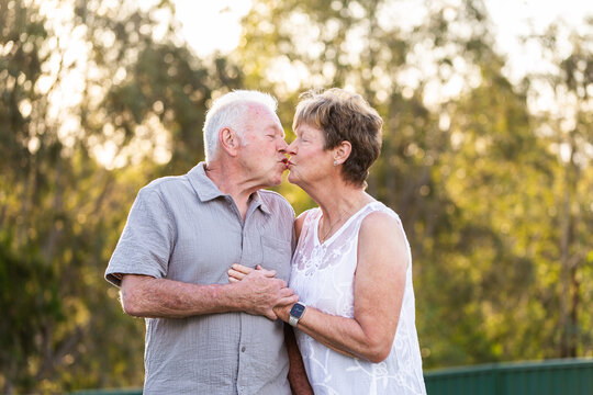 happy senior Australian couple kiss outdoors with golden backlighting