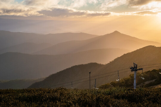Sunset on Mt Buller with ski lift in shot and green foliage in foreground