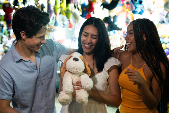 Young friends celebrating a win, holding a stuffed animal prize at a carnival