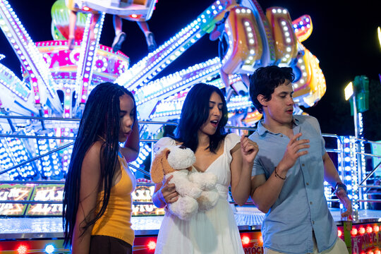 Diverse friends enjoying a fun night dancing at a fair with bright lights