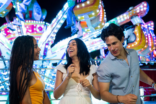 Diverse young adult friends enjoying a night out at an amusement park