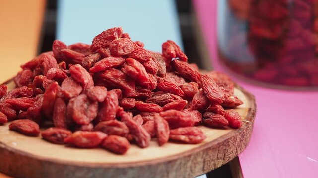 A close up view of dried goji berries on a wooden board with a blurry background, showcasing the vibrant red color of these healthy superfoods