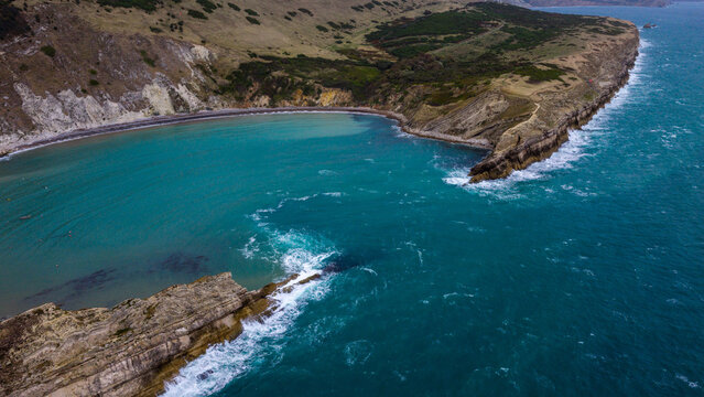 Aerial view of Lulworth Cove with its distinctive circular bay, turquoise waters, and dramatic limestone cliffs along the Jurassic Coast, Wareham, England, United Kingdom.