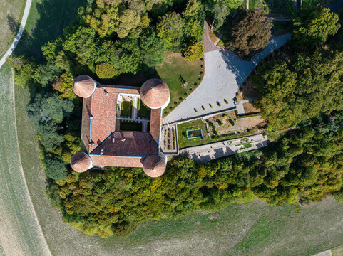 Aerial view of Champvent Castle with its four corner towers and central courtyard surrounded by lush green trees and gardens in Champvent, Vaud, Switzerland.