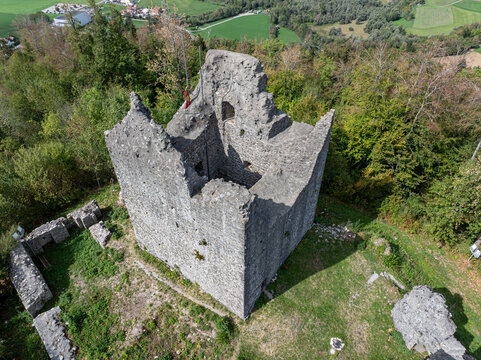 Aerial view of the historic stone ruins of Burg Montsalvens surrounded by lush green forest and rolling hills in Broc, Fribourg, Switzerland.
