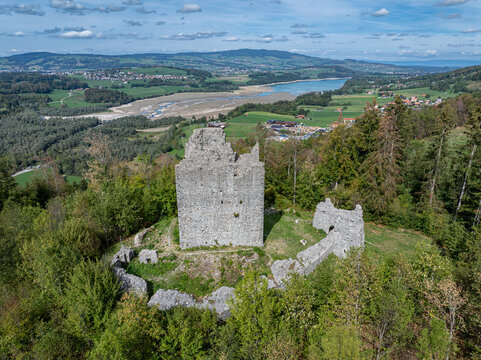 Aerial view of Burg Montsalvens, a historic stone castle ruin surrounded by lush green forests and rolling hills in the Fribourg region, overlooking the landscape near Broc, Fribourg, Switzerland.