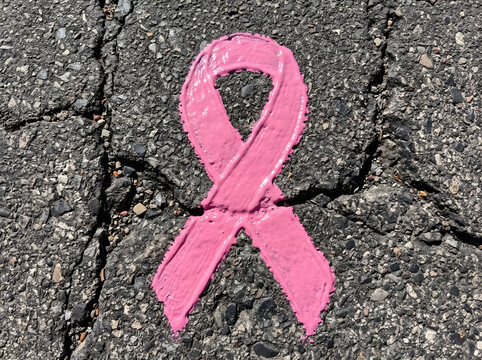 Pink breast cancer awareness ribbon painted on cracked asphalt road