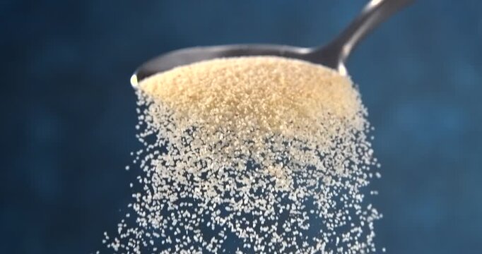 Semolina falling from a spoon in slow motion on blue background