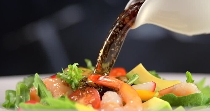 Salad dressing pouring onto fresh shrimp salad in slow motion
