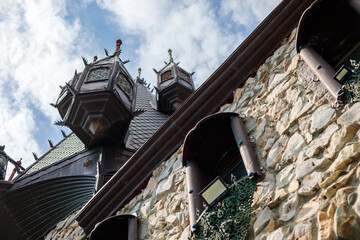 Wooden turrets with dark conical roofs on an old stone building wall, dramatic cloudy sky background, closeup of fairy tale medieval stone architecture, high quality photo © Татьяна Швец