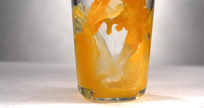 Orange juice pouring into glass in slow motion