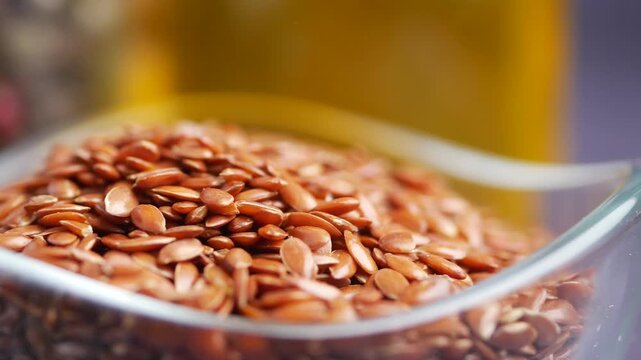 Close up on pile of organic flax seeds in glass bowl with blurred background motion.