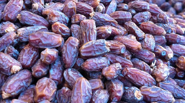 Fresh dried dates fruit texture background during slow panning motion in outdoor marketplace.