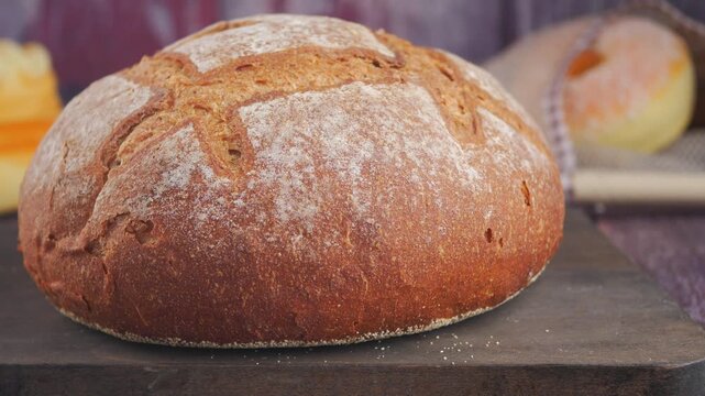 Freshly baked sourdough bread loaf on rustic wooden board with cinematic sliding movement.