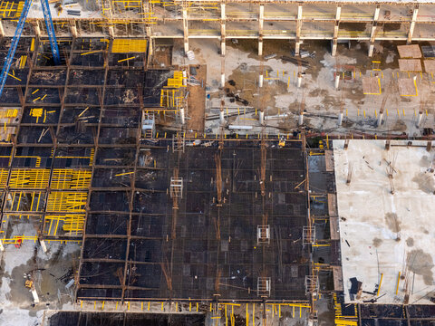 Aerial view of a large construction site featuring exposed steel rebar grids, concrete foundations, and yellow support beams in Santo Domingo Este, Santo Domingo Province, Dominican Republic.