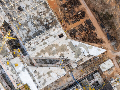 Aerial view of a large construction site featuring concrete foundations, steel reinforcement bars, yellow cranes, and heavy machinery in Santo Domingo Este, Santo Domingo Province, Dominican Republic.
