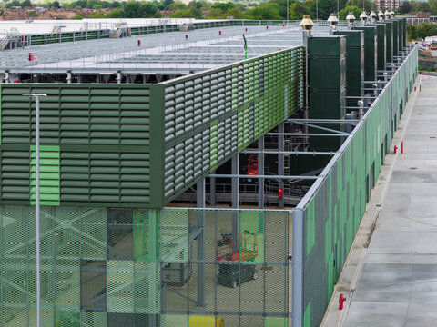 Aerial view of a modern data center featuring green louvered facades, industrial metal mesh panels, and rooftop cooling equipment in the United Kingdom.