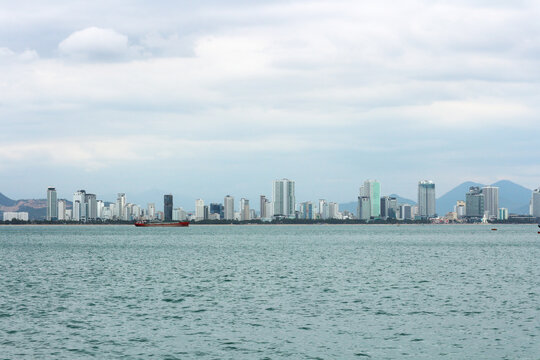 Panoramic coastal cityscape of Nha Trang skyline with high-rise hotels and buildings viewed across the sea from Vinpearl on Hon Tre Island, Vietnam.