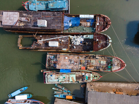 Aerial view of Sleko Harbor featuring several traditional fishing boats moored in the water, with weathered wooden decks, nets, and equipment in Cilacap, Central Java, Indonesia.