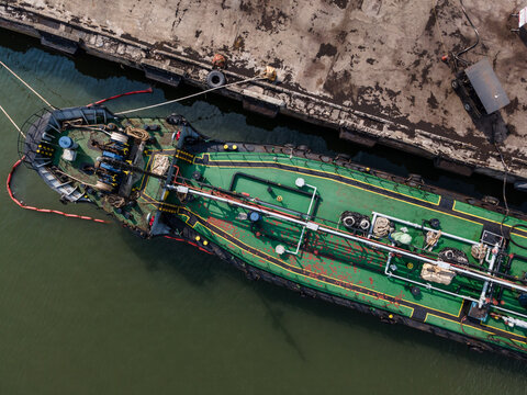Aerial view of the Port of Tanjung Intan Cilacap featuring a green tanker ship moored alongside a concrete pier in Cilacap, Central Java, Indonesia.