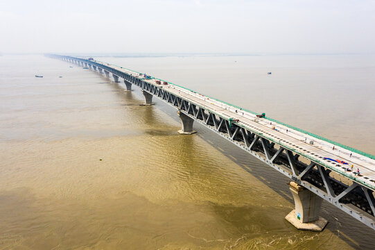 Aerial view of the Padma Bridge spanning the Padma River with construction work visible on the deck in Mawa, Dhaka Division, Bangladesh.