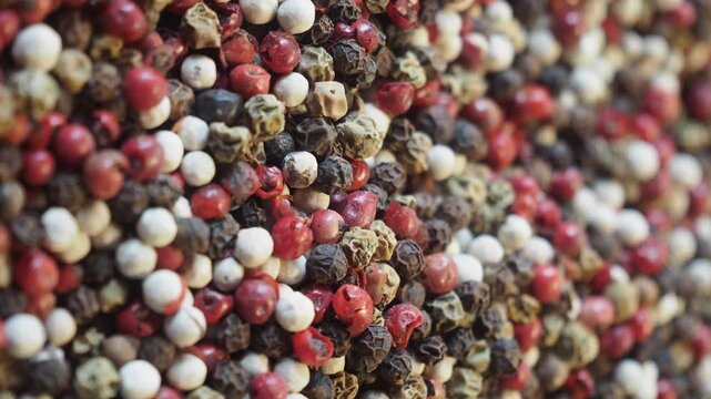 Close up motion of mixed peppercorns, black white red and green spices.
