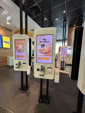 McDonald's self-service kiosk ordering machines with touch screen displays and card payment terminals inside a fast food restaurant in Dubai