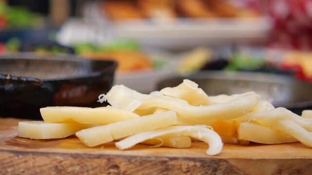 String cheese pieces on wooden board for breakfast meal with selective focus in restaurant.