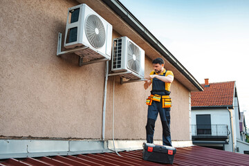 Repairman checking and fixing an hvac system on a building roof © Jelena