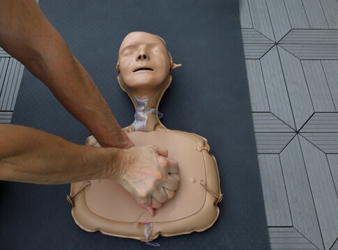 CPR or cardiopulmonary resuscitation practice on a dummy doll. Strong male hand and arm visible. First aid concept.