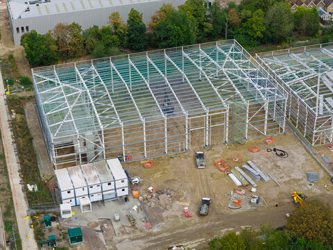 Aerial view of a data center construction site featuring a large steel frame structure, temporary office trailers, and construction equipment in the United Kingdom.