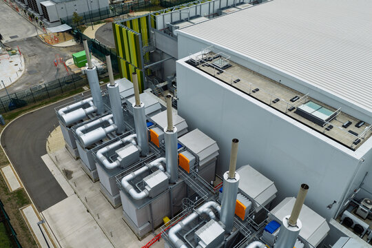 Aerial view of a modern data center facility featuring industrial cooling units and exhaust stacks in the United Kingdom.
