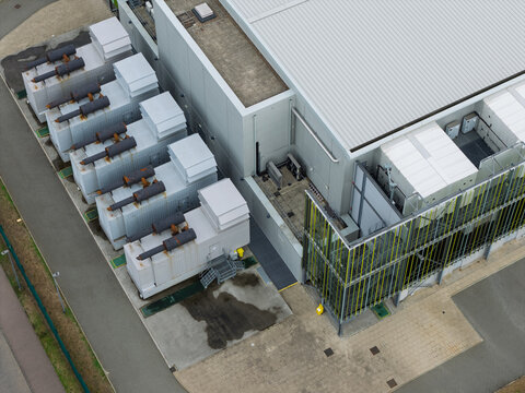Aerial view of a data center facility with industrial cooling units and power generators situated on a paved lot in the United Kingdom.