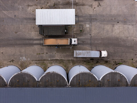 Aerial view of industrial grain silos and trucks parked in a concrete lot in Starogard Gdanski, Poland.