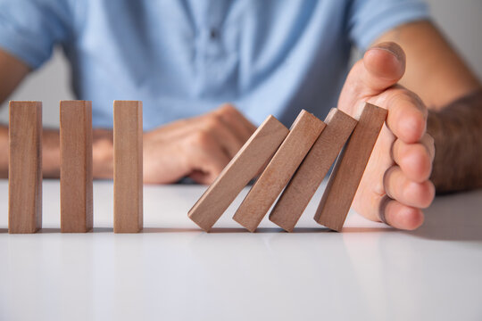 Male hand stopping wooden blocks from falling.
