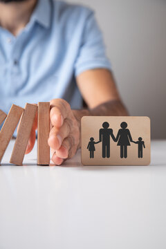 Male hand stopping wooden blocks from falling on family.