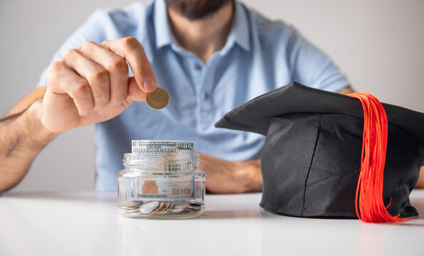 Man showing Graduation Cap with a coins.