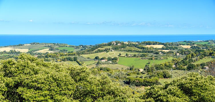 Panoramic view of green hills, fields, and trees overlooking the Adriatic sea between Pesaro and Fano, Italy. A heart shape is visible in the fields in the center