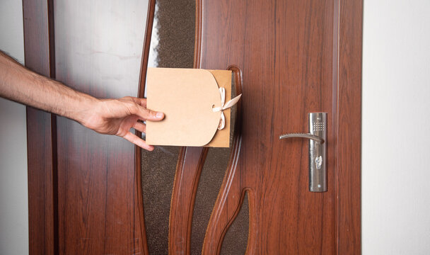 Man holding a gift box waiting in behind the door.