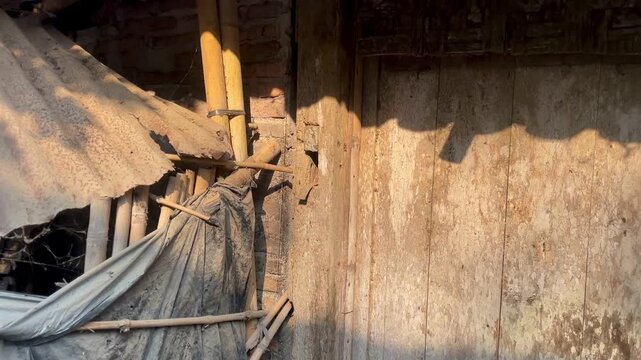 A corner of the exterior of an old, dusty, and dry house, featuring a wooden door bathed in sunlight.