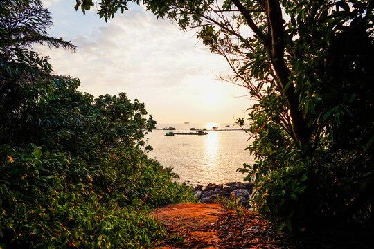 Path to sea at sunset with floating boats. Sunset toward horizon, reflecting in sea water, while fishing boats, Vietnam, Phu Quoc, Tropical Southeast Asia. 