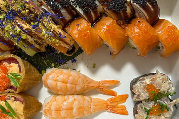 Assorted sushi rolls with salmon and shrimp arranged on a white background for a meal set © ir1ska